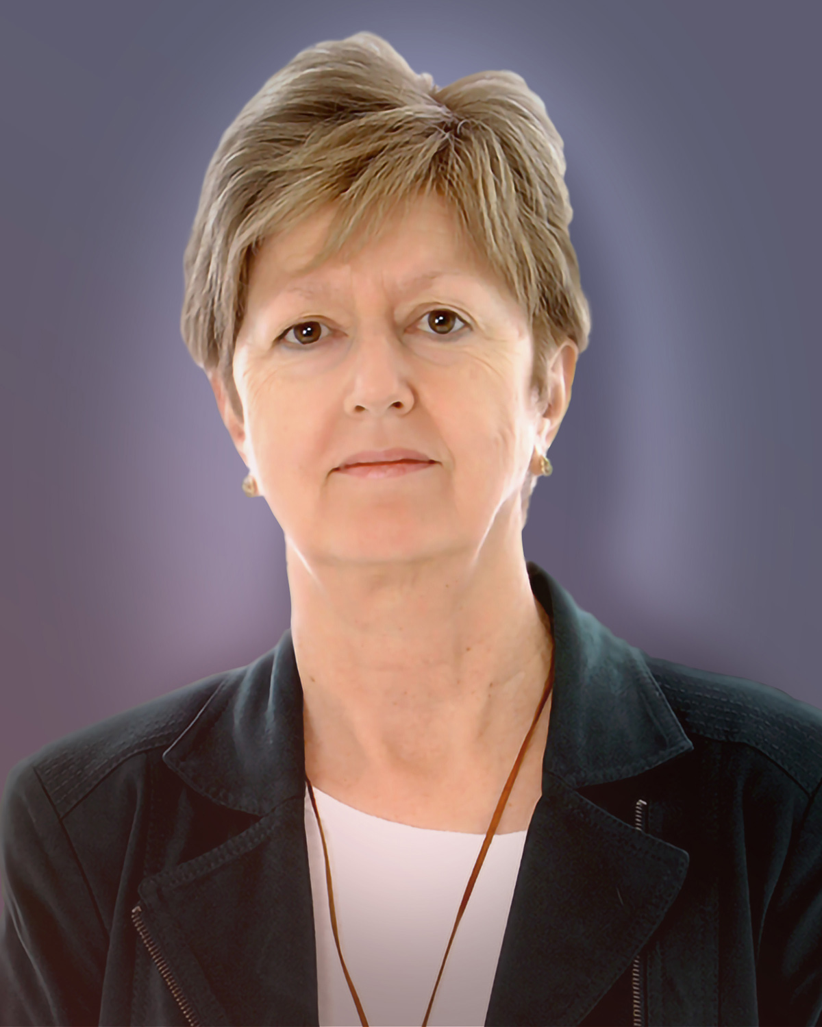 A headshot photo with a purple background of Anne Dokov who is wearing a black blazer over a white top. Anne has short blonde hair and has a gentle smile.