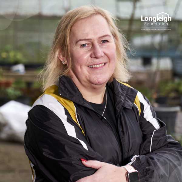 A stock image of a woman smiling and crossing her hand over the top half of her body, on top of a backdrop of Longleigh's artwork background and a image title 'Longleigh's Impact'